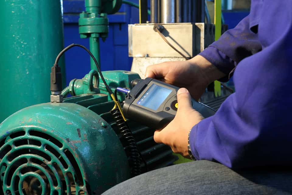 Technician taking readings from an electric motor with a handheld condition monitoring instrument during onsite training