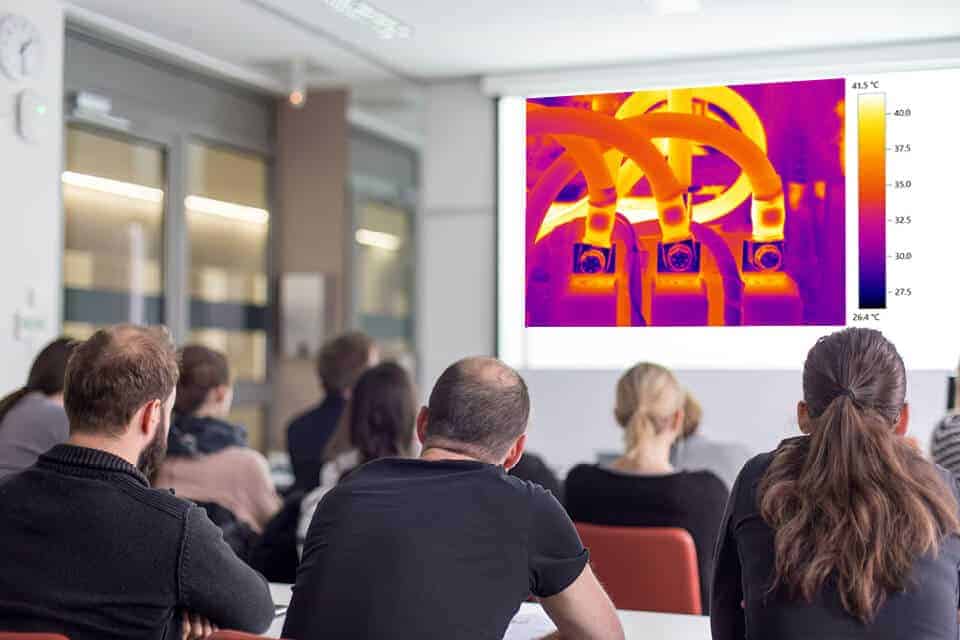 Students in a classroom watching a thermal image of pipework projected on screen during a thermography course